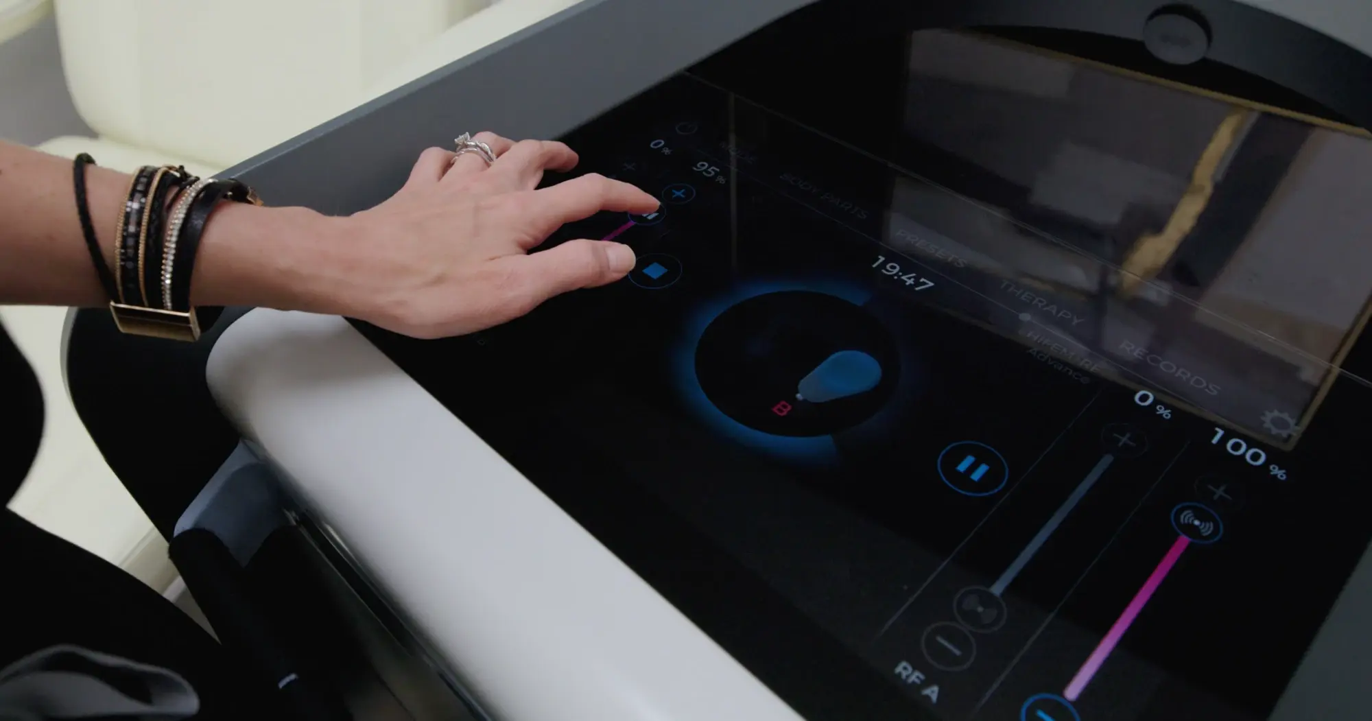 A clinician adjusting the intensity on the EMSCULPT NEO console part-way through a session