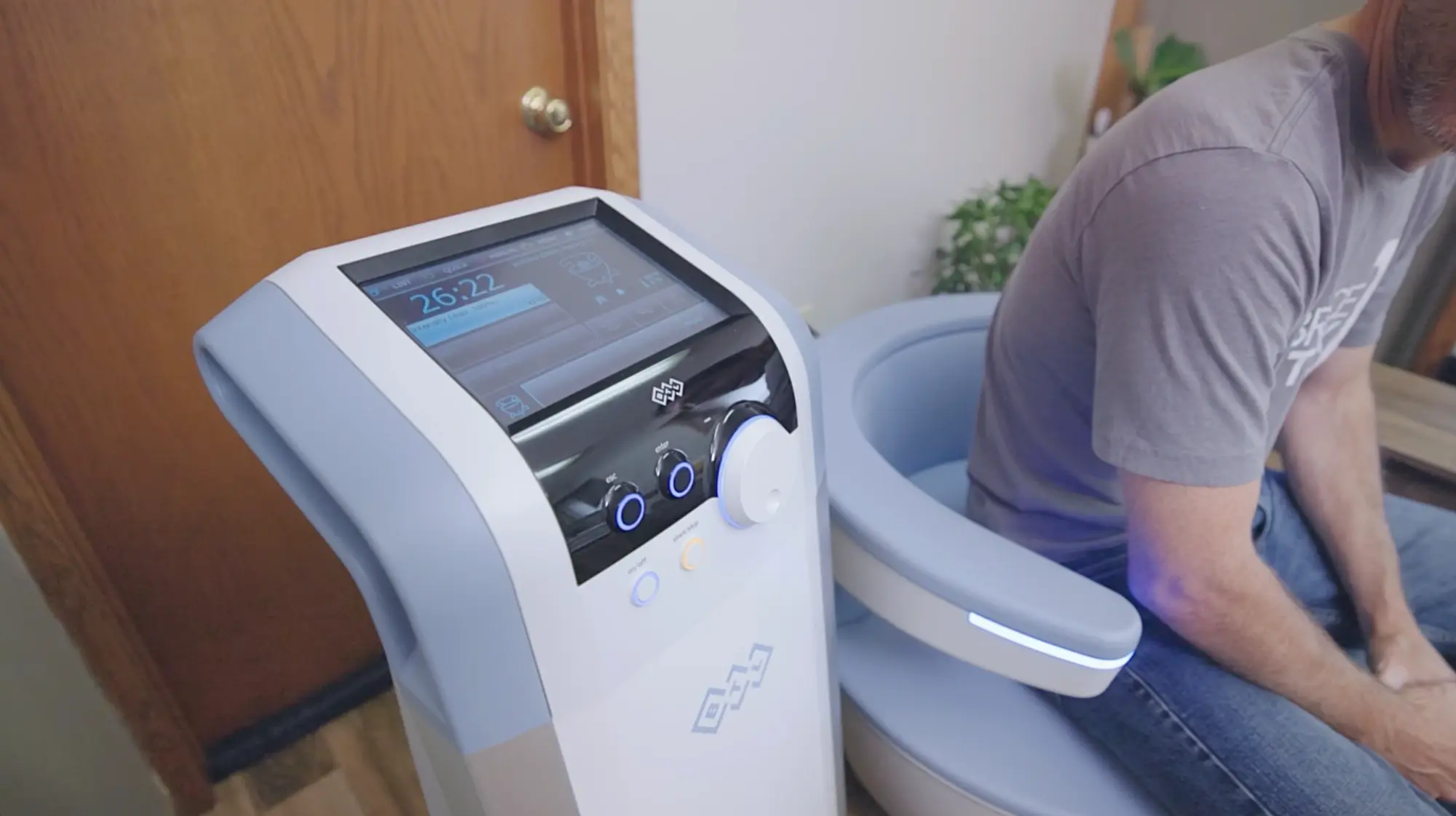 The EMSELLA console counting down a session while a patient sits on the chair